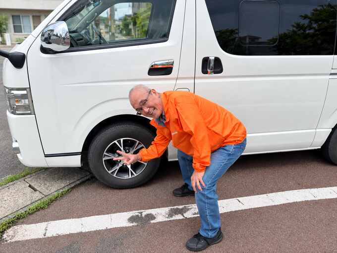 アルミホイールを確認しながら笑顔を見せる小野店長